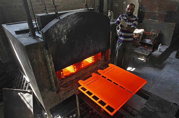 A worker stands next to a room heater manufacturing unit inside a factory in Srinagar.