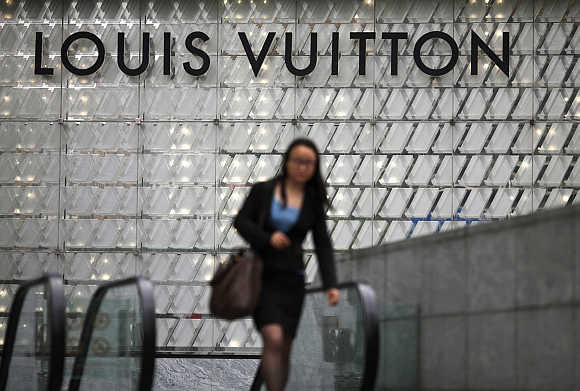 A woman walks by a Louis Vuitton luxury boutique at a mall in Shanghai.