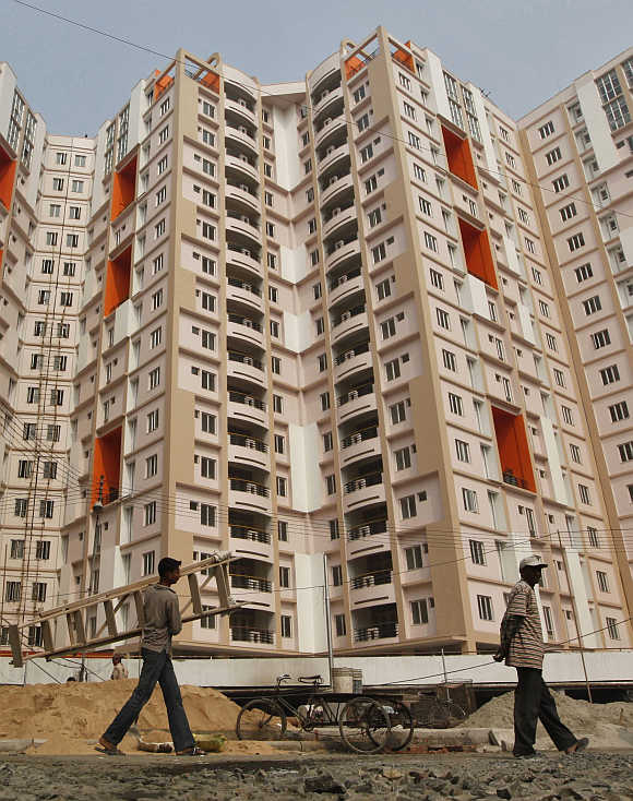 Labourers walk past a residential estate under construction in Kolkata.
