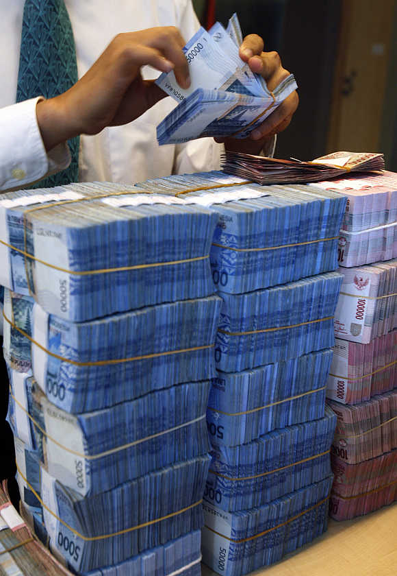 A teller counts packs of rupiah banknotes in Jakarta, Indonesia.