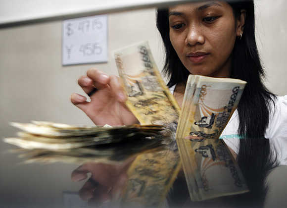 A woman counts peso notes in Manila's Makati financial district.