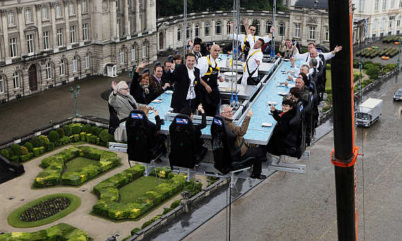 Guests enjoy a 'Dinner in the Sky' on a platform hanging in front of the Royal Palace in Brussels.