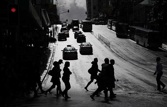 People cross a street after rainfall in central Auckland, New Zealand.
