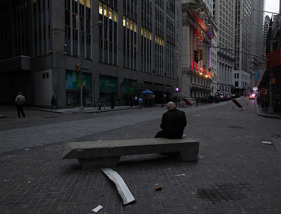 A man sits on a bench in the early morning hours outside the New York Stock Exchange.