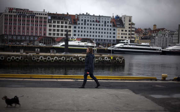 A woman walks her dog near the the marina in downtown Bergen, Norway.
