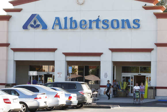 Customers leave an Albertsons grocery store with their purchases in Burbank, California. Albertsons is owned by Supervalu, the third-largest US grocery chain.