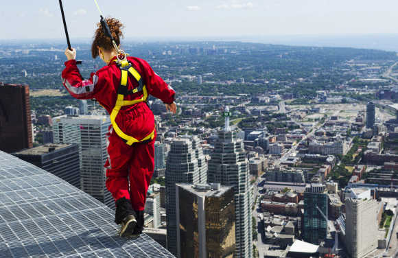 A reporter walks on the edge of the catwalk during the media preview for the 'EdgeWalk' on the CN Tower in Toronto.
