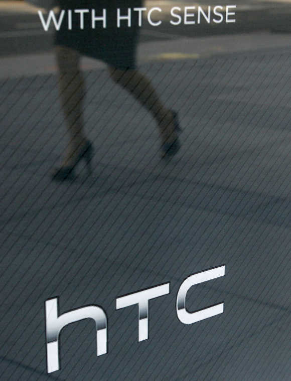 A woman walks past a HTC's window advertisement outside a mobile phone store in Taipei, Taiwan.