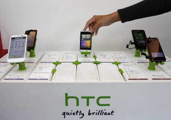 A shop attendant arranges HTC phones in a mobile phone store in Taipei, Taiwan.