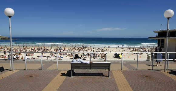 Man rests on a bench overlooking Sydney's famous Bondi Beach.