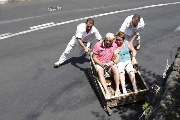Carreiros (sledge drivers) push tourists in Monte on the Atlantic island of Madeira, Portugal.
