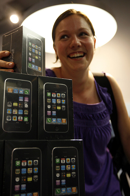 One of the first iPhone buyers in Switzerland poses for photographers next to Apple's new iPhone 3G as it went on sale in Zurich.
