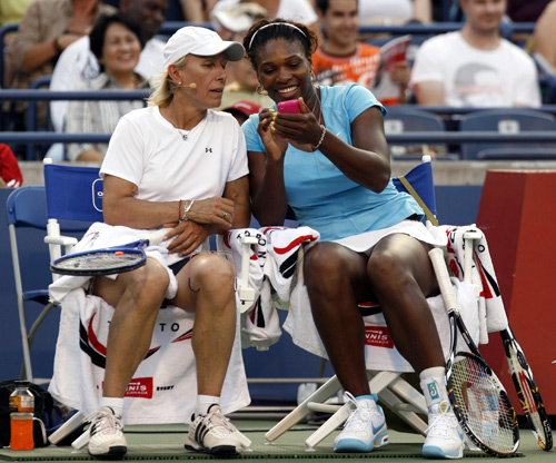 Martina Navratilova (L) looks at Serena Williams' Iphone while playing in an exhibition doubles match at the Rogers Cup tennis tournament in Toronto.