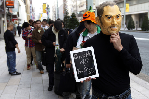 A man wearing a mask of Apple founder Steve Jobs stands in a line to buy an iPhone 4S in front of an Apple Store in Tokyo.