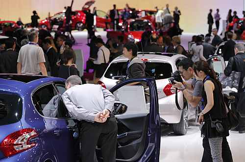 Visitors look at cars on media day at the Paris Motor Show 2012
