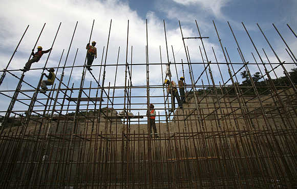 Workers fasten iron rods at the construction site of a bridge in Jammu.