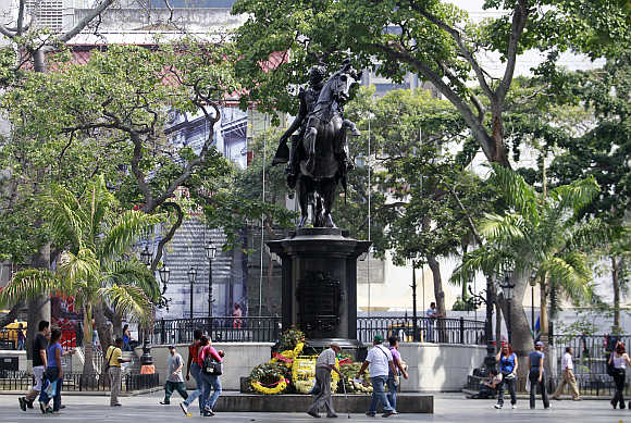 Poeple walk next to the statue of national hero Simon Bolivar in Caracas, Venezuela.