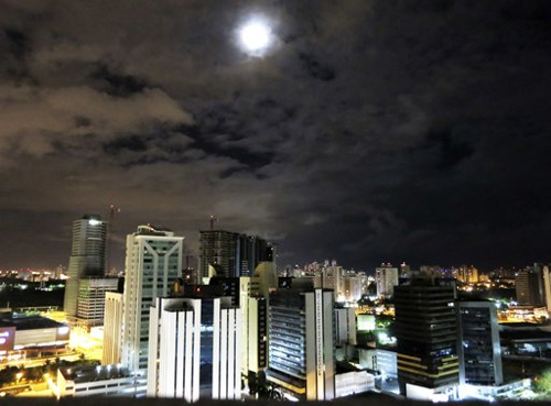 The moon rises above buildings in Salvador, Brazil.