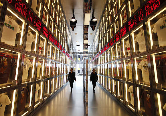 A staff member is reflected in a mirror as she walks at Fast Retailing's flagship Uniqlo store in Tokyo, Japan.