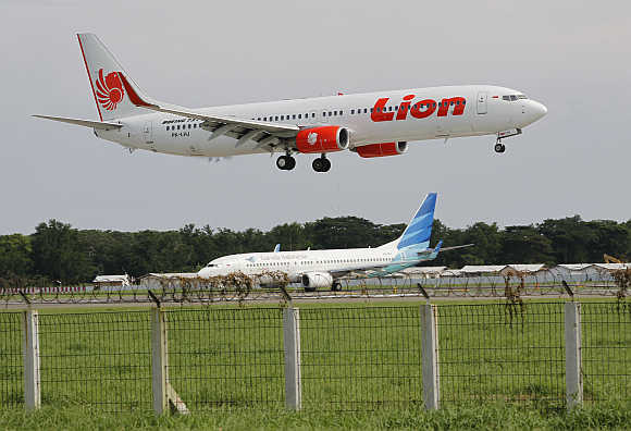 A Lion aeroplane prepares to land as a Garuda plane queues to take-off at the Sukarno-Hatta airport in Tangerang on the outskirts of Jakarta, Indonesia.