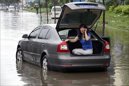 A woman talks on her mobile phone at the trunk of her car as she waits for rescue on a flooded street in Taiyuan, Shanxi province.