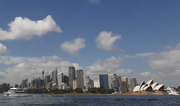 A catamaran leaves the central business district, with the Sydney Opera House in the background, in Sydney, Australia.