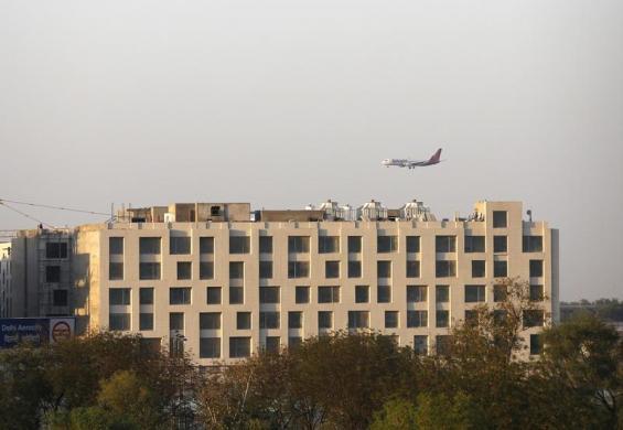 A SpiceJet Airlines aircraft flies past newly-constructed hotels on the way to landing at the Indira Gandhi International Airport in New Delhi.