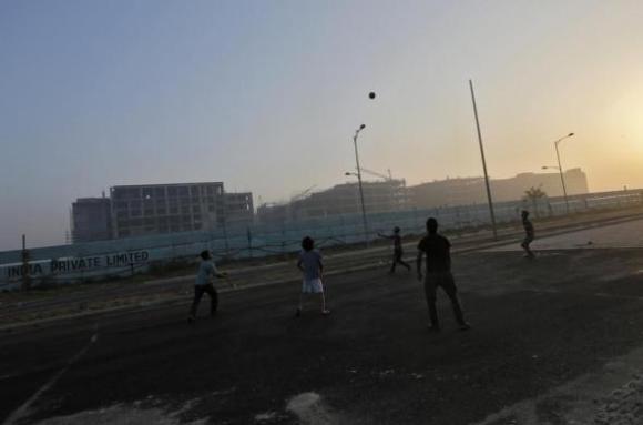 Youths play with a ball in front of hotels being constructed outside the Indira Gandhi International Airport in New Delhi