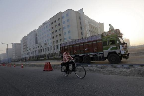 A man rides his bicycle past newly-constructed hotels outside the Indira Gandhi International Airport in New Delhi.