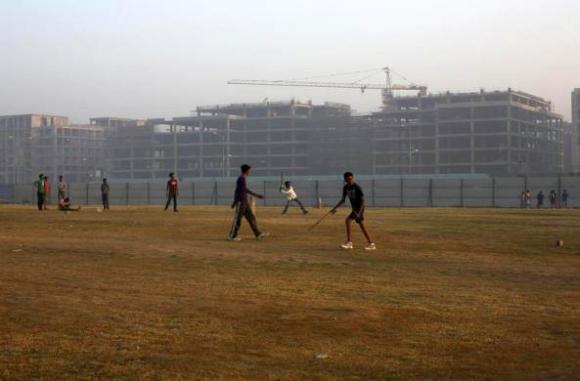 Youths play cricket in front of hotels being constructed outside the Indira Gandhi International Airport in New Delhi.