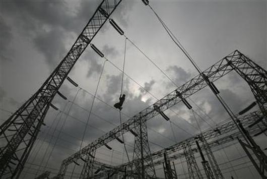 A worker installs an electric power cable on a pylon.