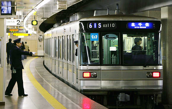 A worker gestures as a car at Tsukiji subway station of Tokyo Metro Hibiya Line moves off in Japan.