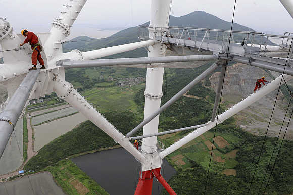 Labourers work on the Damaoshan power transmission tower in Zhoushan, Zhejiang province, China.