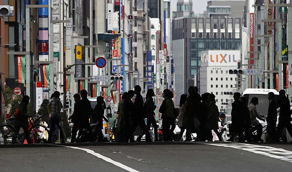 Pedestrians cross a street at Tokyo's Ginza shopping district in Japan.