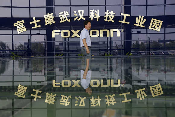 A man walks past a logo of a Foxconn factory in Wuhan, Hubei province, China.