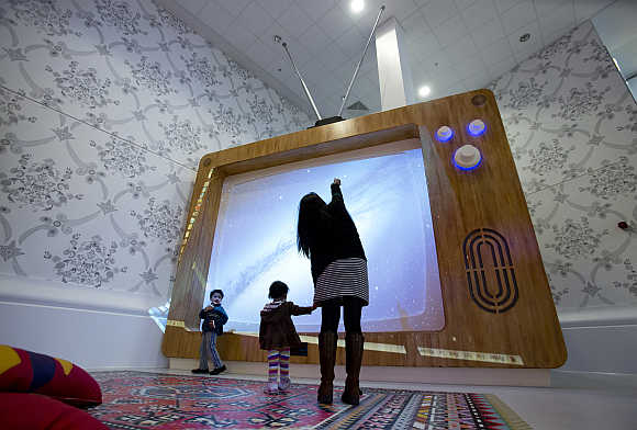 A woman and young children interact with a giant television set at the Ann Riches Healing Space for young patients at the Royal London Hospital in London, United Kingdom.