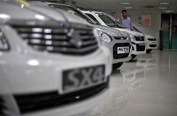 A sales executive speaks on his mobile phone as he stands in between Maruti Suzuki cars inside a showroom in New Delhi.