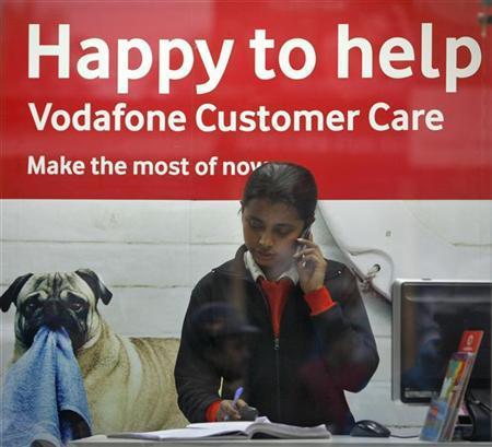 An employee talks on mobile phone inside a Vodafone store.
