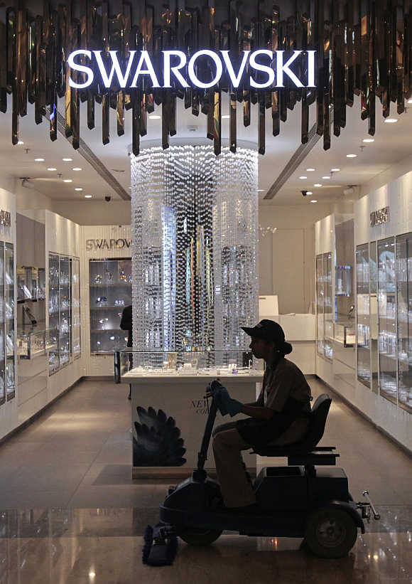 An employee operates a floor cleaning machine in front of a Swarovski showroom inside a shopping mall in Mumbai.