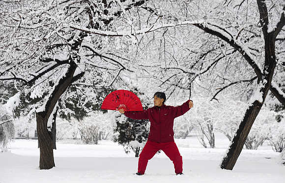A woman practices tai chi with a fan after a snowfall in Shenyang, Liaoning province.