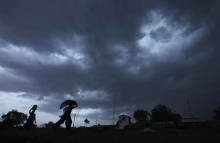 A girl runs for cover as it rains as monsoon clouds gather over Meerwada village in Guna district in Madhya Pradesh.