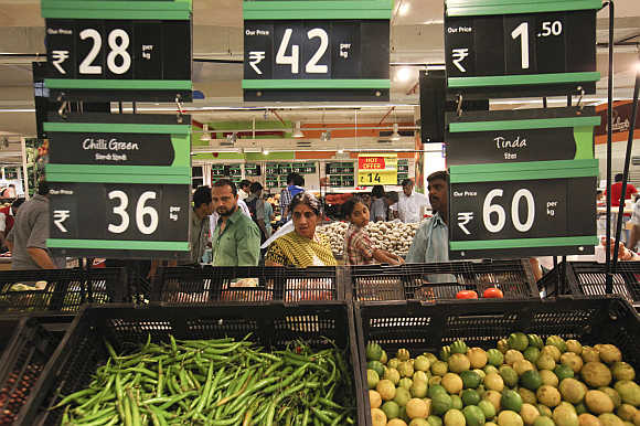 Prices for various vegetables are displayed as people shop in the fresh foods section of a Reliance Fresh supermarket in Mumbai.