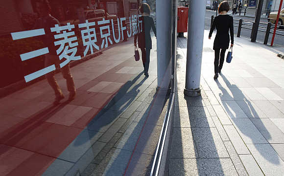 A pedestrian walks past a signboard of a branch bank of Mitsubishi UFJ Financial Group in Tokyo.