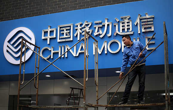 A labourer works in front of a sign for China Mobile at the company's office in downtown Shanghai.
