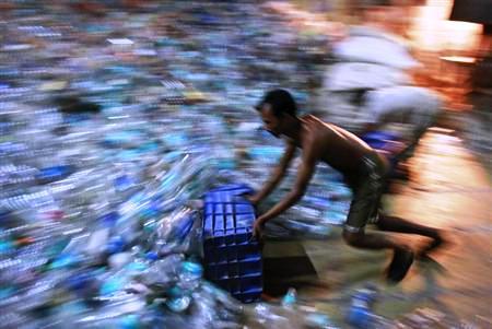 A man collects empty plastic bottles to be recycled at a factory in a slum in Mumbai.