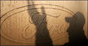 The shadow of a worker is seen on the logo of Ford Motor Co