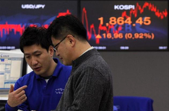 Foreign currency dealers from the Korea Exchange Bank are seen in front of a monitor displaying the current Korea Composite Stock Price Index (KOSPI) at the KEB in Seoul.