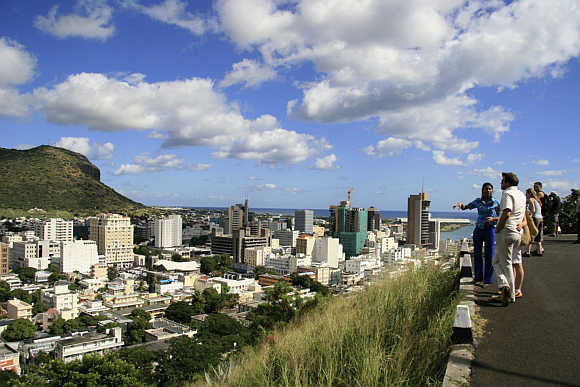A tour guide with a group of tourists at a viewpoint overlooking Port Louis in Mauritius.