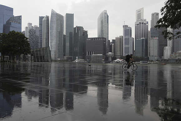 A cyclist rides past the skyline of the Central Business District in Singapore.
