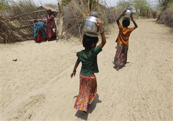 Village girls carry metal pitchers filled with water supplied by the government in Gujarat.